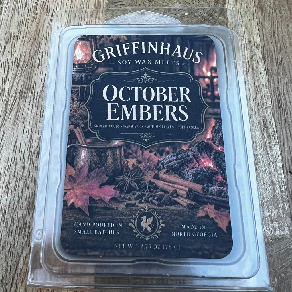 Griffinhaus Soy Wax Melts in the 'October Embers' scent, packaged in a clear plastic clamshell container and placed on a rustic wooden surface.